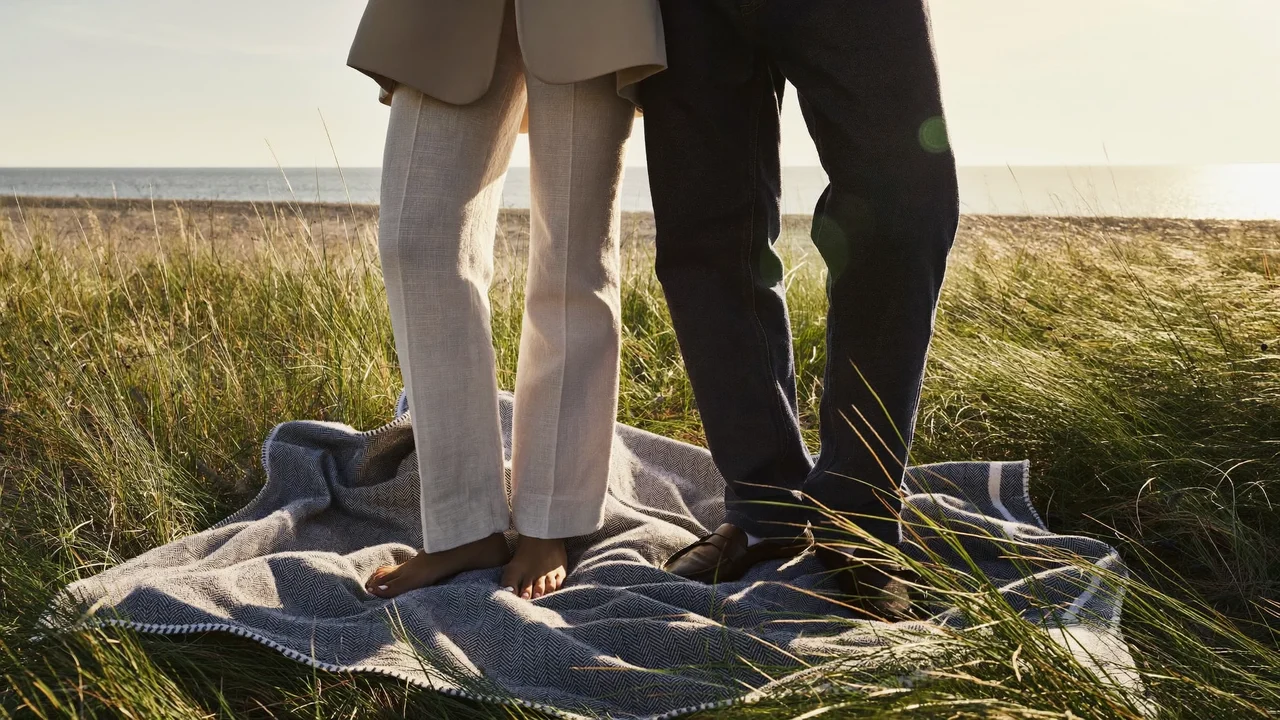 Tæppe og klitgræs ved en dansk strandpicnic i gyldent aftenlys